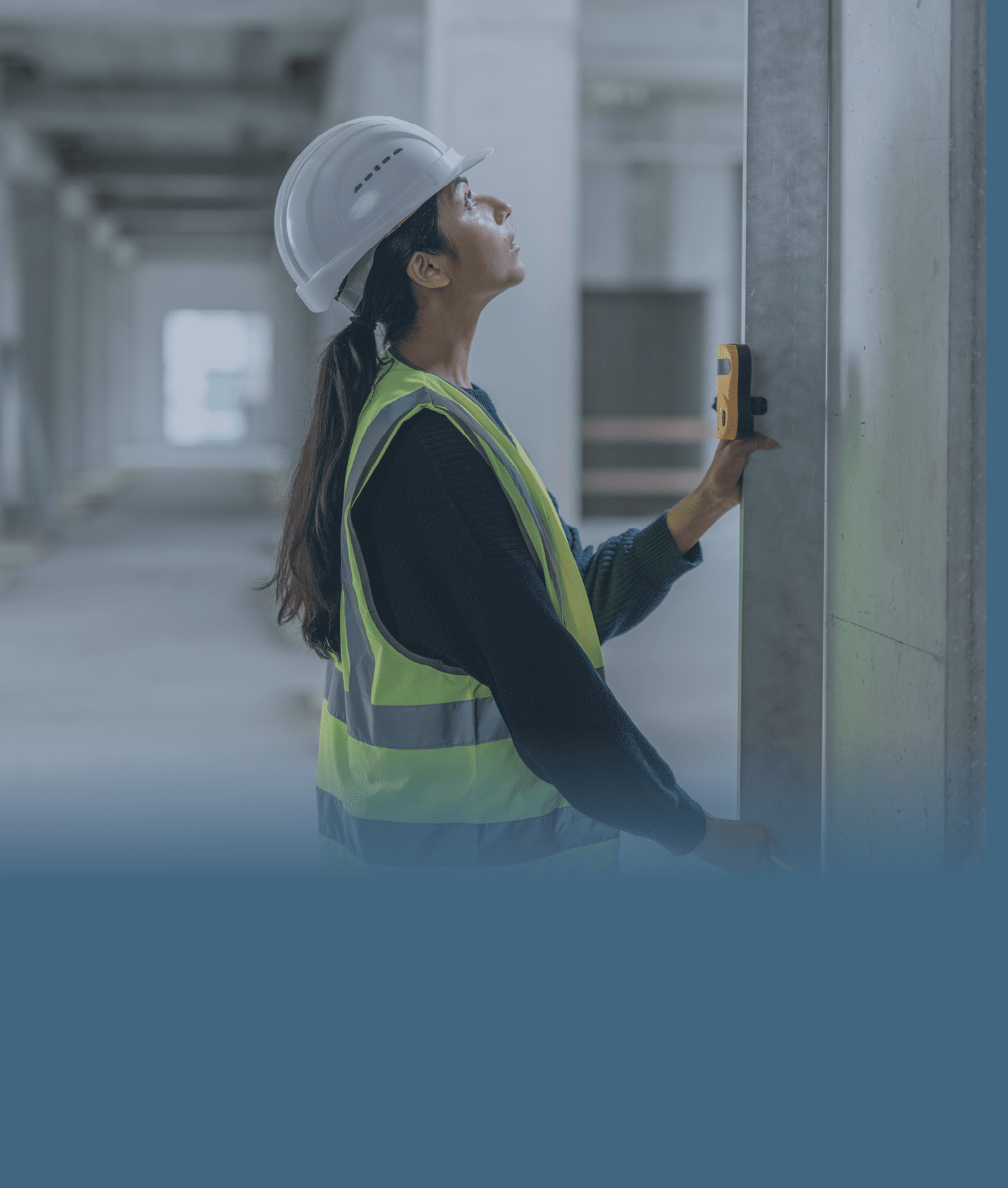 Young female construction worker measuring concrete support beam with laser spirit level at site.